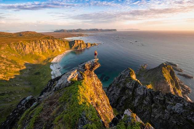  Abendstimmung, Wanderin steht am Abgrund auf Felsvorsprung, Blick auf Felsen, Strand und Meer, Gipfel des Berges Matinden, bei Stave, Nordland, Norwegen, Europa *** Evening atmosphere, hiker standing on a cliff, view to rocks, beach and sea, peak of the mountain Matinden, near Stave, Nordland, Norway, Europe Copyright: imageBROKER/MoritzxWolf ibxmmw06270299.jpg