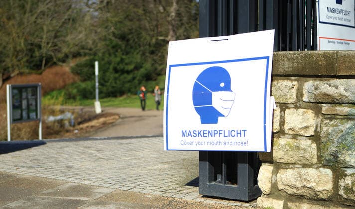 Am Eingang einer Grünanlage in der Hamburger Innenstadt hängen Schilder, die darauf hinweisen, dass in diesem Park am Wochenende und an Feiertagen von 10 bis 18 Uhr Maskenpflicht besteht. Innenstadt Hamburg