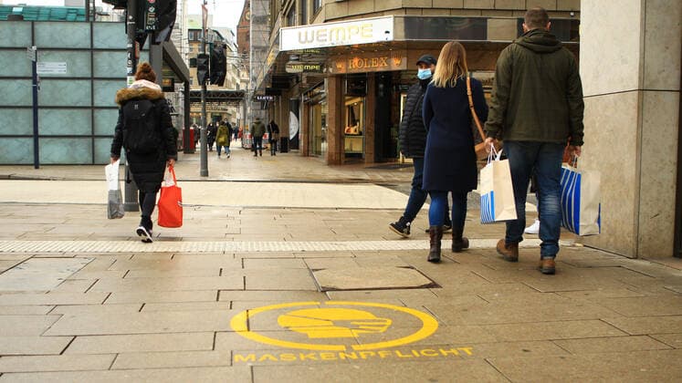 Auf die Plastersteine am Jungfernstieg in der Hamburger Innenstadt ist der Hinweis gesprüht, dass hier Maskenpflicht besteht. Innenstadt Hamburg