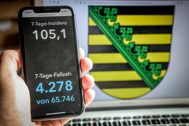 Coronavirus in Deutschland - Covid-19-Dashboard des Robert Koch-Institut DEU, Deutschland, Sachsen, 14.03.2021: Die 7-Tage-Inzidenz für das Bundesland (Fälle letzte 7 Tage 100.000 EW) wird auf einem iPhone angezeigt, im Hintergrund das Landeswappen