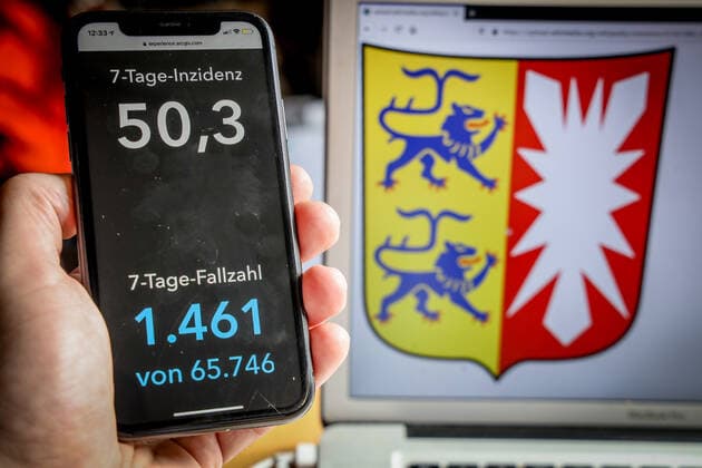 Coronavirus in Deutschland - Covid-19-Dashboard des Robert Koch-Institut DEU, Deutschland, Schleswig-Holstein, 14.03.2021: Die 7-Tage-Inzidenz für das Bundesland (Fälle letzte 7 Tage 100.000 EW) wird auf einem iPhone angezeigt, im Hintergrund das Landeswappen