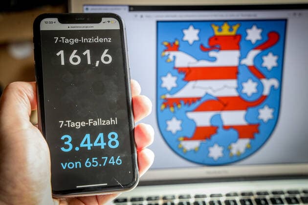 Coronavirus in Deutschland - Covid-19-Dashboard des Robert Koch-Institut DEU, Deutschland, Thüringen, 14.03.2021: Die 7-Tage-Inzidenz für das Bundesland (Fälle letzte 7 Tage 100.000 EW) wird auf einem iPhone angezeigt, im Hintergrund das Landeswappen