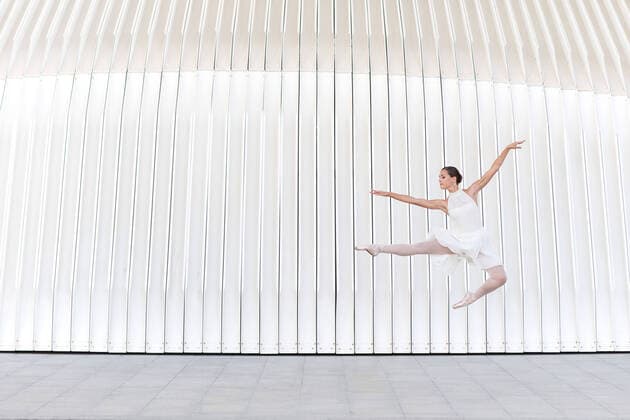 IMAGO Creative: Stadt-Dichotomien Young female ballet dancer in pointe shoes with raised leg and arm jumping over tiled pavement Copyright: xAdrianxVilanovax Model Released