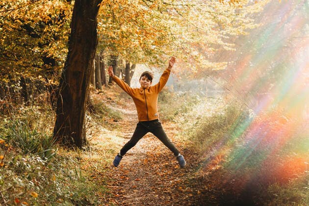 IMAGO Creative, Jahreszeit Herbst, Ferien Boy leaping in the air on path under tree with rainbow light flare Fleet, England, United Kingdom CR_CEHE210312I-678391-01 ,model released, Symbolfoto