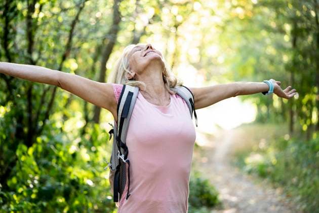 Smiling mature woman stretching arms while standing in forest Copyright: FrédéricxCirou B72807346
