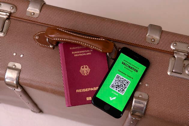 17.03.2021, Symbolbild, Impfung. Ein imaginärer Impfpass in digitaler Form auf dem Smartphone iPhone, bereitgelegt auf einem Reisekoffer mit einem Reisepass. Der digitale Impfpass würde wieder uneingeschränktes Reisen ermöglichen, 17.03.2021, Elektronischer Impfpass für Urlaubsreisen 17.03.2021, Elektronischer Impfpass für Urlaubsreisen