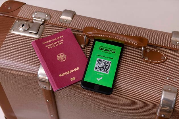 17.03.2021, Symbolbild, Impfung. Ein imaginärer Impfpass in digitaler Form auf dem Smartphone iPhone, bereitgelegt auf einem Reisekoffer mit einem Reisepass. Der digitale Impfpass würde wieder uneingeschränktes Reisen ermöglichen, 17.03.2021, Elektronischer Impfpass für Urlaubsreisen 17.03.2021, Elektronischer Impfpass für Urlaubsreisen