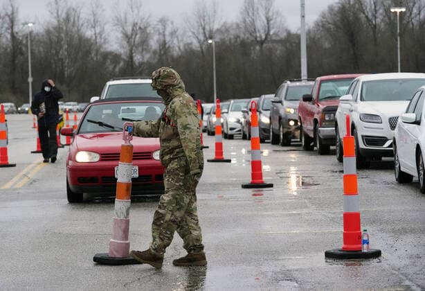 Missouri National Guardsmen direct traffic as cars line up for vaccination shots at the Family Arena during a mass vaccination drive-in event in St. Charles, Missouri on Thursday, March 18, 2021. The event attracted 4,000 people, some waiting over four hours in their cars for their first shot to protect them from the coronavirus.  SLP2021031814 BILLxGREENBLATT