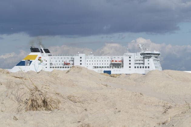 Die RoPax-Fähre Nils Holgersson der deutschen Fährschiffreederei TT-Line läuft am Donnerstag (18.03.2021) in Warnemünde ein während im Vordergrund die Dünen zwischen Strand und Strandpromenade zu sehen sind. Gegenwärtig sind in dem Ostseebad, bedingt durch die Corona – Pandemie, nur wenige Ausflügler zwischen dem Teepott und dem Hotel Neptun unterwegs. Der Fährverkehr zwischen Rostock und dem schwedischen Trelleborg läuft jedoch nach wie vor weiter. Nur jedoch mit wesentlich weniger Passagieren. Ob sich das zu Ostern ändern wird ist bisher völlig unklar. Eine Entscheidung könnte am Montag (22.03.2021) beim Bund-Länder-Gipfel mit der Bundeskanzlerin Angela Merkel und den Länderchefs fallen.