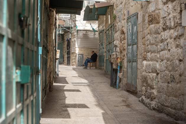 (210320) -- BETHLEHEM, March 20, 2021 -- A Palestinian man sits near closed shops in the West Bank city of Bethlehem, March 20, 2021. The Governor of Bethlehem announced on Thursday the closure of the governorate and a ban on all activities from Thursday evening until Sunday morning due to increasing numbers of COVID-19 infection. (Photo by Xinhua) MIDEAST-BETHLEHEM-COVID-19-LOCKDOWN LuayxSababa 