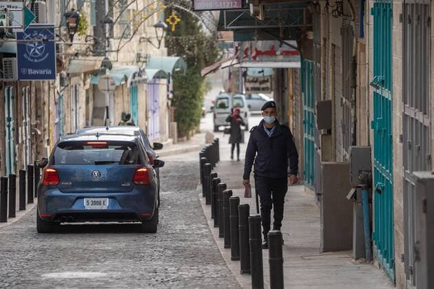 (210320) -- BETHLEHEM, March 20, 2021 -- A Palestinian police officer walks by closed shops in the West Bank city of Bethlehem, March 20, 2021. The Governor of Bethlehem announced on Thursday the closure of the governorate and a ban on all activities from Thursday evening until Sunday morning due to increasing numbers of COVID-19 infection. (Photo by Xinhua) MIDEAST-BETHLEHEM-COVID-19-LOCKDOWN LuayxSababa 
