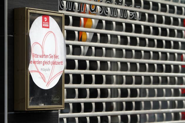 An einem mit Rolltor geschlossenen Restaurant hängt noch ein Aufkleber aus der Lockerung im letzten Sommer: Bitte warten Sie hier, Sie werden gleich platziert in der Innenstadt von Frankfurt, Hessen, Deutschland