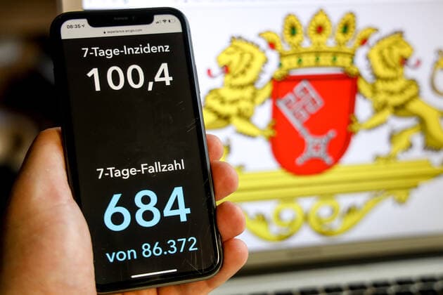 Coronavirus in Deutschland - Covid-19-Dashboard des Robert Koch-Institut DEU, Deutschland, Bremen, 21.03.2021: Die 7-Tage-Inzidenz für das Bundesland (Fälle letzte 7 Tage 100.000 EW) wird auf einem iPhone angezeigt, im Hintergrund das Landeswappen