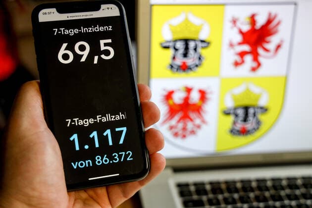 Coronavirus in Deutschland - Covid-19-Dashboard des Robert Koch-Institut DEU, Deutschland, Mecklenburg-Vorpommern, 21.03.2021: Die 7-Tage-Inzidenz für das Bundesland (Fälle letzte 7 Tage 100.000 EW) wird auf einem iPhone angezeigt, im Hintergrund das Landeswappen