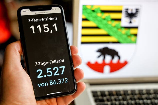 Coronavirus in Deutschland - Covid-19-Dashboard des Robert Koch-Institut DEU, Deutschland, Sachsen-Anhalt, 21.03.2021: Die 7-Tage-Inzidenz für das Bundesland (Fälle letzte 7 Tage 100.000 EW) wird auf einem iPhone angezeigt, im Hintergrund das Landeswappen
