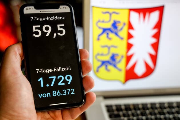 Coronavirus in Deutschland - Covid-19-Dashboard des Robert Koch-Institut DEU, Deutschland, Schleswig-Holstein, 21.03.2021: Die 7-Tage-Inzidenz für das Bundesland (Fälle letzte 7 Tage 100.000 EW) wird auf einem iPhone angezeigt, im Hintergrund das Landeswappen