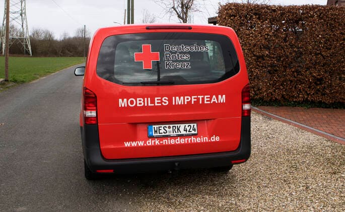 DRK Einsatzfahrzeug Mobiles Impfen Einsatzfahrzeug des DRK Wesel mit der Aufschrift Mobiles Impfteam. Das Fahrzeug wird genutzt zum Transport der Impfdosen zu den Impfzentren oder ambulanten Impforten. Das Fahrzeug steht vor einem Privathaus. Moers Deutschland Nordrhein-Westfalen NRW