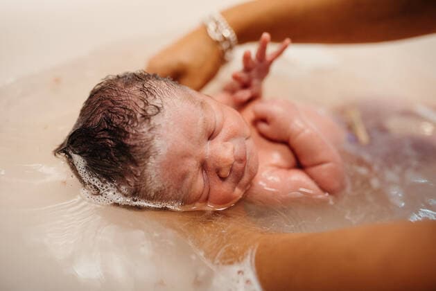 High angle of cute newborn child held by anonymous mother getting bath in sink, Model released Copyright: xOierxAsox MR