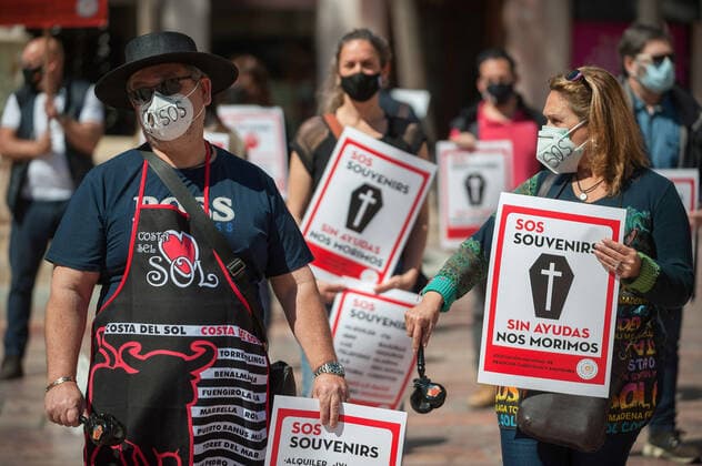 March 23, 2021, Malaga, Spain: Protesters wearing masks hold placards at Plaza de la Constitucion square during the demonstration..Employees from S.O.S Souvenirs association in Malaga, who work in tourists stores of souvenirs, demand the Spanish government sector survival facing fall incomes due to coronavirus pandemic. Many tourist stores and shops have had to close after restrictions of tourist sector and arrivals of tourists in Spain. Malaga Spain - ZUMAs197 20210323_zaa_s197_006 Copyright: xJesusxMeridax
