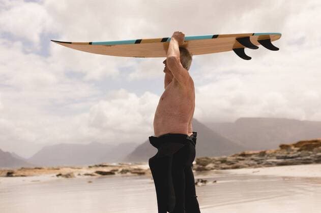 IMAGO Creative: Sommer Sport - Strand Senior man carrying surfboard on his head at beach Side view of active senior man carrying surfboard on his head at beach against relief background, model released, capetown, 12.02.2019, 1228311.jpg, senior citizen, aged, retired, pensioner, active senior, sportwear, standing, holding, smiling, surfer, surfboard, surfing, water sport, sport, beach, shore, ocean, wave, cloud, cloudy, sky, nature, environment, tranquility, serenity, calm, peaceful, scenic, beautiful, travel, travel destination, tourism, holiday, vacation, shirtless, diving suit, background, mountains, relief 70s, Senior, Elderly, Man, Male, Caucasian, Senior Men, Caucasian Ethnicity Outdoors