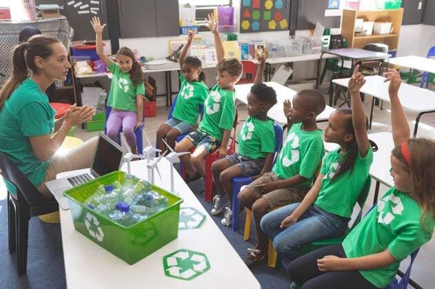 School kids wearing recycle tee-shirt raising hand to answer at a question Side view of school kids wearing recycle tee-shirt raising hand to answer at a question asking by their teacher sitting in front of them, model released, , property released, Cork, Ireland, 05.02.2019, 1238655.jpg, school, classroom, desk, bench, uniform, school kid, schoolboy, schoolgirl, student, classmate, schoolteacher, schoolmaster, chalkboard, magnifying glass, windmill, green energy, environment, energy, ecology, renewable resources, conservation, sustainable, recycle bin, studying, sitting, talking, discussing, teaching, explaining, hand raised, answering, attentive, focused, concentration, childhood, innocence, development, education, academic, information