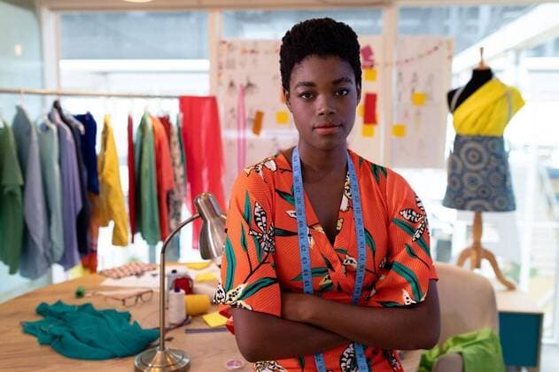 Female fashion designer sitting with arms crossed in design studio Portrait of young pretty African american female fashion designer sitting with arms crossed in design studio. This is a casual creative start-up business office for a diverse team, model released, , property released, Cape Town, South Africa, 17.03.2019, 1266730.jpg, gen z, generation z, fashion designer, designer, dressmakers, tailor, measuring tape, professional, creative, design, expertise, fashion industry, textile, business, local, start up business, start up, entrepreneur, small business, beginning, local business, artisan, maker, individuality, craft, skill, retail, table, mannequin, casual clothing, curly hair, sitting, looking, arms crossed, hands folded, modern, s
