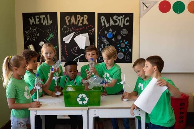 IMAGO Nature: Unsere Erde, Umweltverträgliche Herausforderungen des 21. Jahrhunderts, Recycling Group of schoolchildren wearing green t shirts with a white recycling logo on them standing around a Diverse elementary school being socially concious. Group of schoolchildren wearing green t shirts with a white recycling logo on them, model released, , property released, Cape Town, South Africa, 01.12.2019, 1303835.jpg, people,real people,class,classmates,school,elementary school,primary school,classroom,education,lesson,student,pupil,childhood,learn,learning,together,interacting,communication,information,knowledge,development,environmental issues,eco,green,recycling,awareness,care,environment,climate,energy,resources,pollution,ecology,values,youth,future,concern,climate change,global warming,green t shirt,wind turbine,poster,project,team