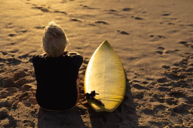 IMAGO Creative: Sommer Sport - Strand Old woman with a surfboard at the beach Rear view of a senior Caucasian woman at the beach at sunset, sitting on the sand with a surfboard beside her, looking out to sea, model released, , property released, Cape Town, South Africa, 21.11.2019, 1313682.jpg, people,real people,enjoy,enjoying,pleasure,lifestyle,free time,holidays,vacation,weekend,activity,relaxing,health,healthy,outdoorsy,fit,leisure,beach,coast,coastal,sand,sunny,summer,retirement,sport,sports,surfing,surfboard,sportswear,wetsuit,happy,confident,freedom,water sport,sports equipment,hobbies,sunset,sundown,sitting,tranquility,thinking,active seniors Senior,Elderly,Woman,Female,Caucasian Outdoors,Rear view,Focus on Foreground,Looking Away,Single object,Dusk-Twilight,Full lengt