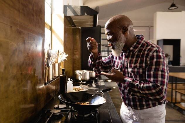 African chef tasting the vegetables Side view of an African American Senior man at a cookery class, tasting hot vegetables. Active Seniors enjoying their retirement., model released, , property released, Cape Town, South Africa, 05.12.2019, 1317561.jpg, people,dish,tasting,vegetables,pan,wok,cooking,frying,work station,chefs whites,uniform,counter top,real people,restaurant,business,food,kitchen,cookery,cuisine,culinary,catering,profession,job,experience,skill,busy,service,professional,confident,work,worker,working,preparation,preparing,making,chef,head chef,class,training,student,teacher,teaching,learning,education,workshop,cook,active seniors,retirement Mature Adult,Man,Male,Black Indoors,Day