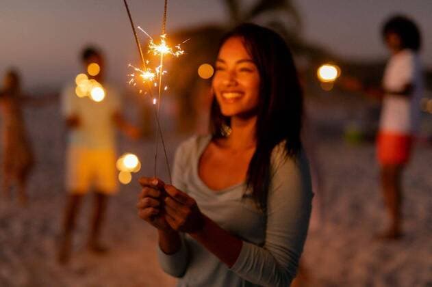 Multi-ethnic group of male and female dancing with firework stick Mixed race woman enjoying her time at the beach with her friends during sunset, holding sparklers, looking at them and smiling with her friends in the background, model released, , property released, Cape Town, South Africa, 25.02.2020, 1345516.jpg, people,blurred,holding,sparklers,real people,happy,smiling,friends,friendship,together,gen z,generation z,holidays,vacation,beach,sea,ocean,tropical,coast,summer,beachwear,seaside,enjoying,sun,leisure,freedom,free time,time off,relaxing,fun,escapism,weekend Young Adult,Woman,Female,Caucasian,Man,Male,Mixed-Race Outdoors,Side view,Focus on Foreground,Five objects,Dusk-Twilight,Half length,Full frame background
