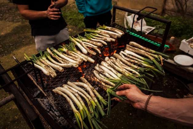 Friends preparing Calcots on barbecue while standing at backyard model released Symbolfoto ACPF01149