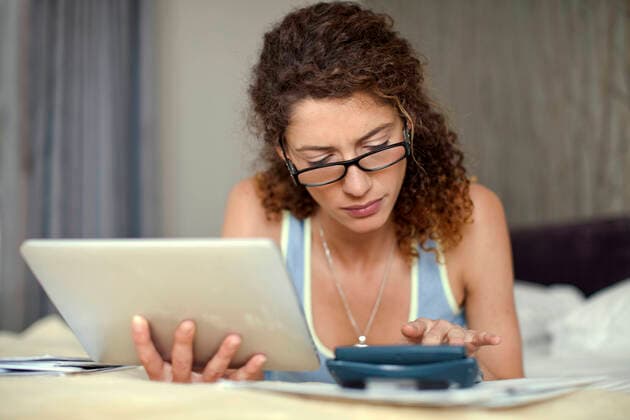Young woman calculating while using digital tablet in bedroom model released Symbolfoto property released AJOF01142