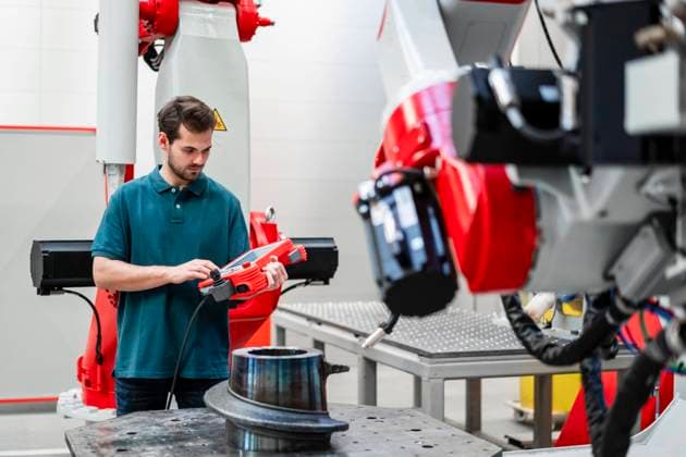 IMAGO Creative: Digitale Welt, Mixed Reality Male engineer operating robotics through control while standing in factory model released Symbolfoto property released DIGF14564