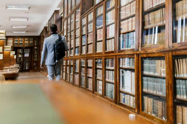 Businessman with backpack walking in library model released Symbolfoto property released EGAF01906