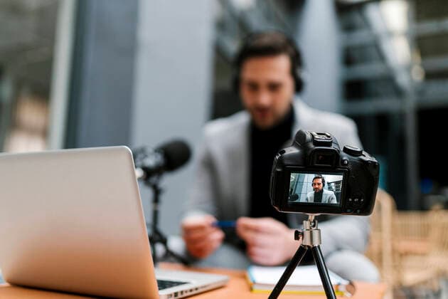 Businessman filming vlog through camera while sitting at cafe model released Symbolfoto property released EGAF01920