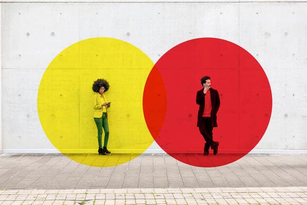 Two overlapping circles visualizing social distancing covering man and woman standing outdoors with smart phones in hands model released Symbolfoto property released EIF00402