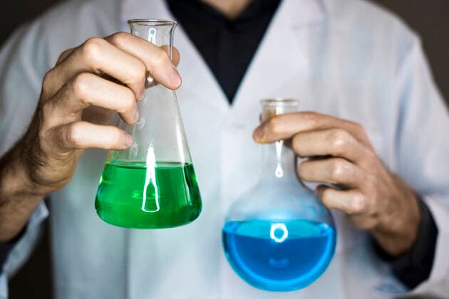 Scientist holding flasks with liquids in laboratory model released Symbolfoto property released GIOF11600