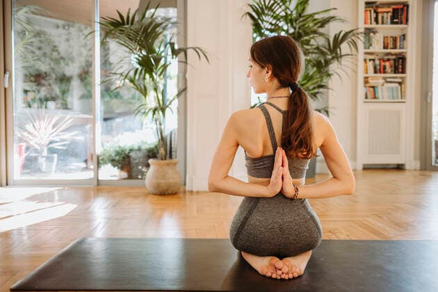 Active woman practicing reverse prayer pose on mat at home model released Symbolfoto property released GMCF00083