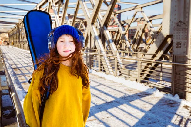 Girl with eyes closed listening music through headphones while standing on bridge model released Symbolfoto IHF00416