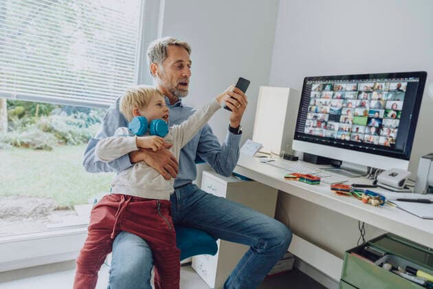 Son distracting father through smart phone while video conferencing at home office model released Symbolfoto property released MFF07200