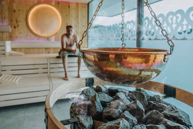 IMAGO Creative, Jahreszeit Winter, Wellness im Spa Container hanging over coal while mature man in background at finnish sauna model released Symbolfoto property released MFF07357
