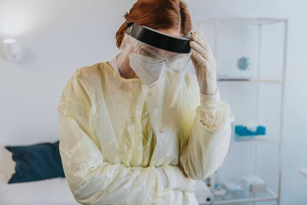 Female healthcare worker wearing protective workwear standing with hand in hand at examination room model released Symbolfoto property released MFF07405