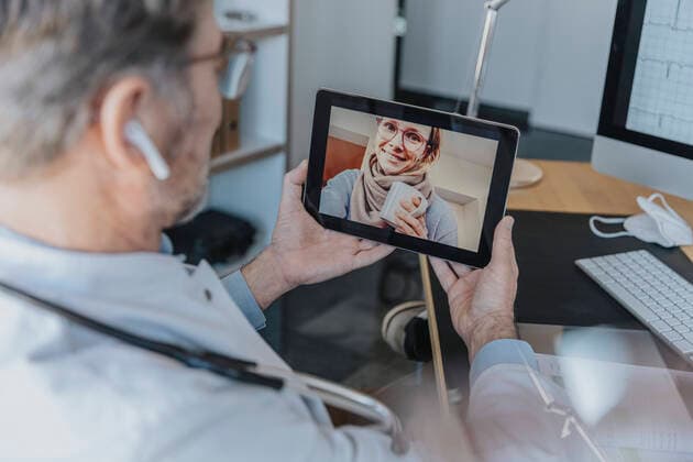 IMAGO Creative: Lokalhelden - Gesundheits- und Rettungskräfte Male healthcare worker talking to patient over digital tablet while sitting at doctor s office model released Symbolfoto property released MFF07595
