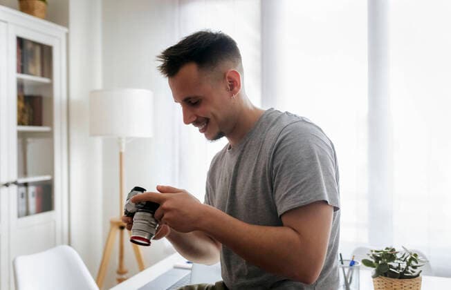 IMAGO Creative: Kreative Renaissance -- der junge Entrepreneur Smiling male entrepreneur holding camera at home office model released Symbolfoto property released MGOF04689
