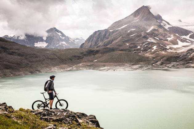 Mountain biker looking at view of Griessee lake while standing at Nufenenpass, Valais, Switzerland model released Symbolfoto MSUF00503