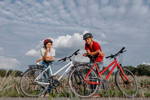 Daughter with father leaning on bicycle while standing at agricultural field against cloudy sky model released Symbolfoto OGF00922