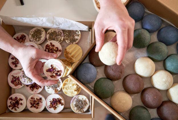 Female entrepreneur s hands holding handmade soaps over table model released Symbolfoto property released VEGF04000