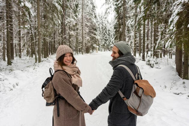 IMAGO Creative: Countdown bis Weihnachten, Nach Hause reisen Young woman smiling while holding hand of man standing in forest model released Symbolfoto VPIF03524