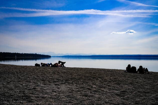 Frühlingswetter am Ammersee 25.03.2021: Ausflügler bei Frühlingswetter am Ufer des Ammersees bei Stegen (Inning am Ammersee; Oberbayern) mit Blick in Richtung Alpen. Inning Bayern Deutschland
