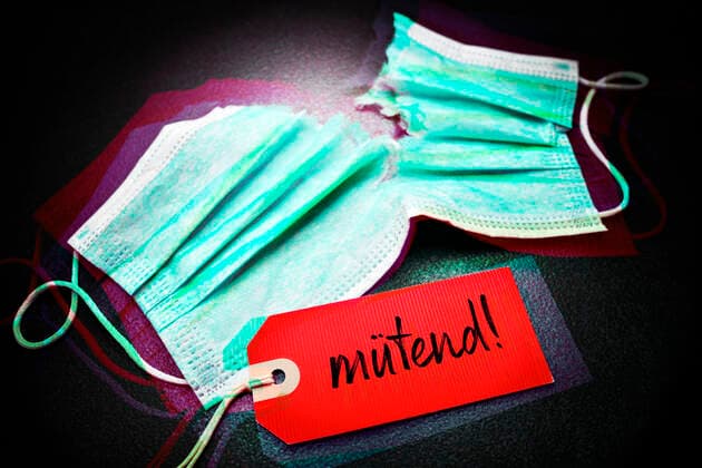 FOTOMONTAGE, Zerrissene OP-Maske mit Etikett und der Aufschrift mÃ¼tend , gemischter Begriff aus wÃ¼tend und mÃ¼de